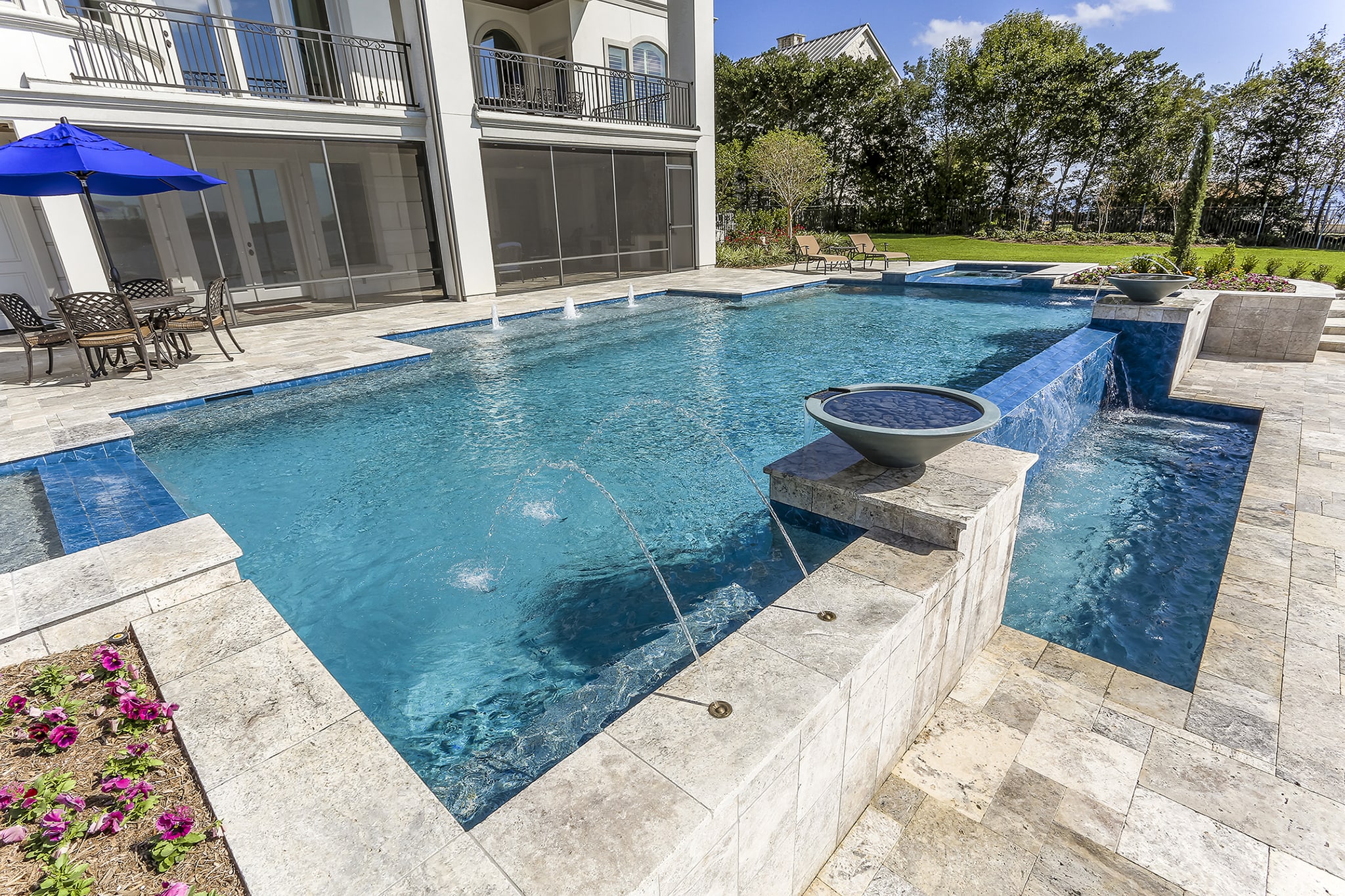 Texas Pools custom pool with water features beside a home and open lawn